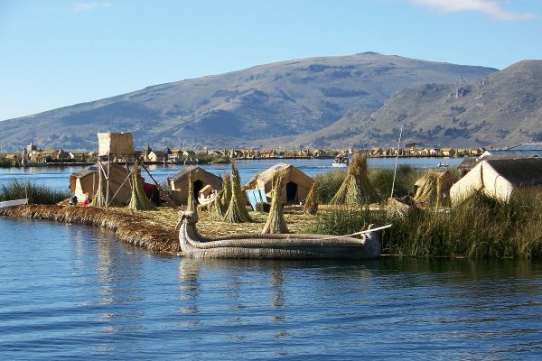 view onto a floating island with little houses made of straw and a canoe on the shore