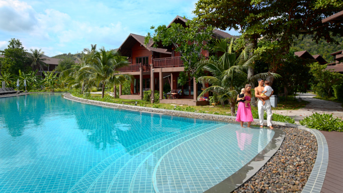 A family standing next to big pool in a resort in Thailand - one of the best international places to travel with toddlers.