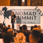 Julia Jerg standing on Nomad Summit stage giving a speech.