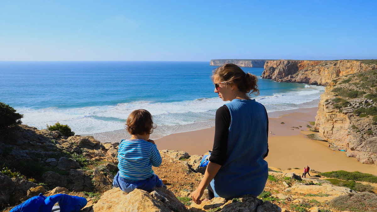 Mother and her son from  the back sitting on rocks overlooking the ocean and cliffs.