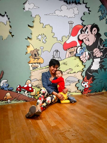 A mother and her child sitting in front of a painted wall with comics which makes Brussels one of the best international places to travel with toddlers.