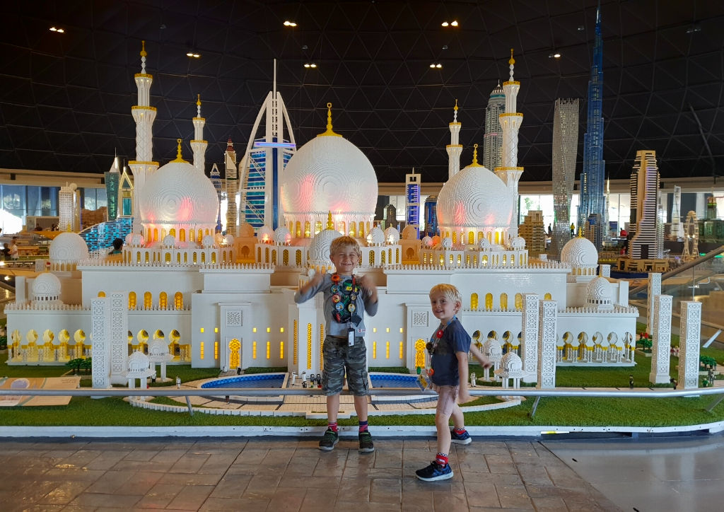 Two little kids in front of a miniature Arabic mosque.